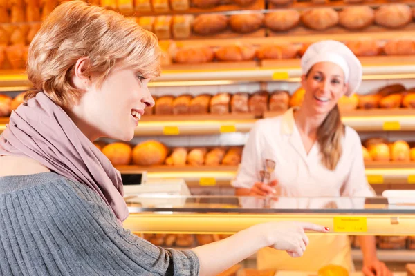 Verkoper met vrouwelijke klant in bakkerij — Stockfoto