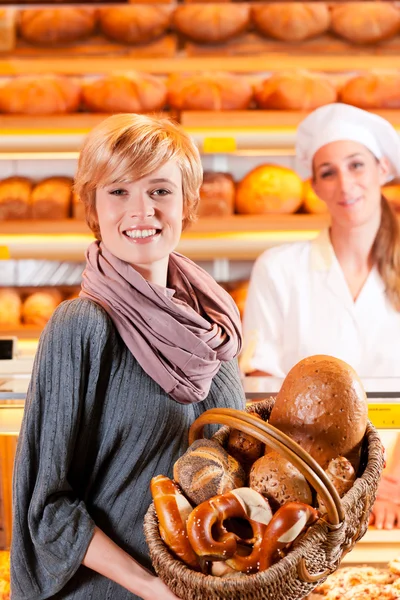 Commerciante con cliente femminile in panetteria — Foto Stock