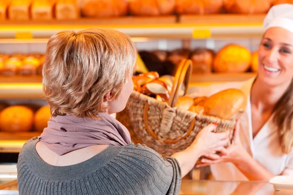 Verkoper met vrouwelijke klant in bakkerij — Stockfoto