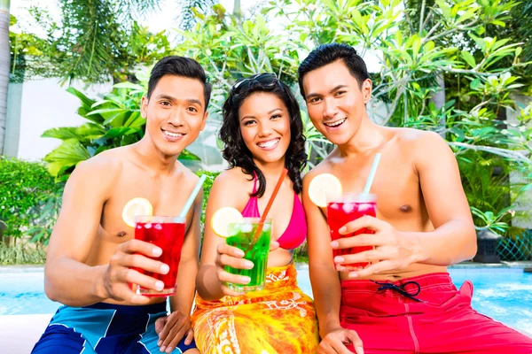 Asian friends drinking cocktails at pool — Stock Photo, Image