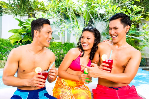 Amigos asiáticos bebendo coquetéis na piscina — Fotografia de Stock