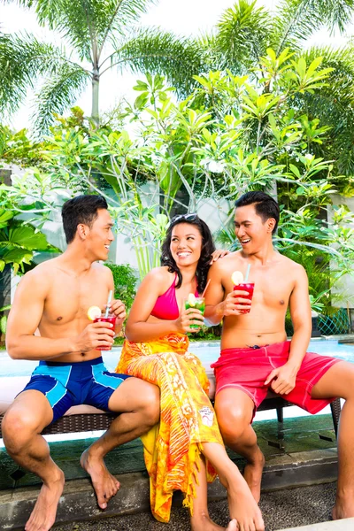 Amigos asiáticos bebendo coquetéis na piscina — Fotografia de Stock