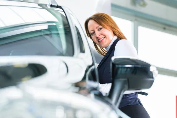 Junge Frau mit Auto in Autohaus — Stockfoto