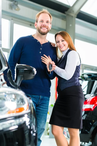 Couple with auto in car dealership — Stock Photo, Image