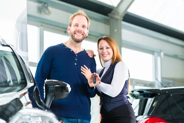Couple with auto in car dealership — Stock Photo, Image