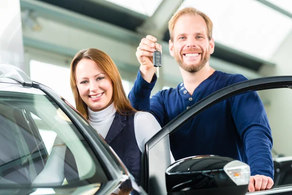 Junger Mann mit Auto in Autohaus — Stockfoto