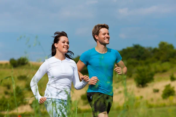 Joven pareja deportiva está corriendo fuera — Foto de Stock