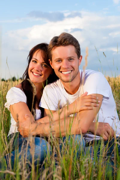 Lyckliga paret sitter på en grainfield — Stockfoto