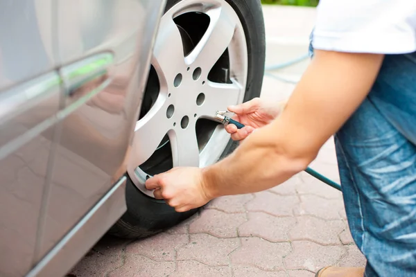 El hombre está controlando la presión de los neumáticos del coche — Foto de Stock