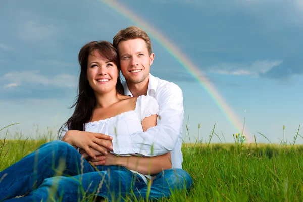 Casal em um prado abaixo do arco-íris — Fotografia de Stock