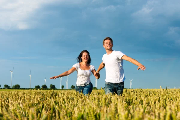 Casal feliz correndo sobre o campo de grãos — Fotografia de Stock