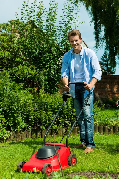 Homem está cortando o gramado no verão — Fotografia de Stock