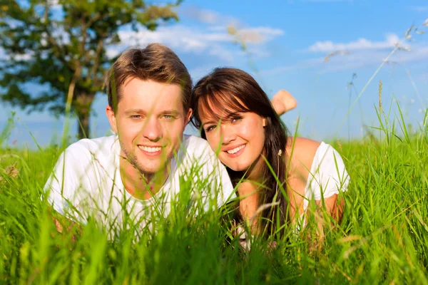 Casal feliz deitado em um prado — Fotografia de Stock