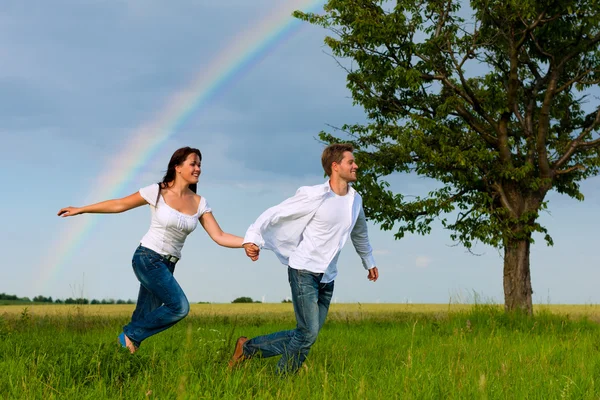 Casal feliz que corre em um prado — Fotografia de Stock