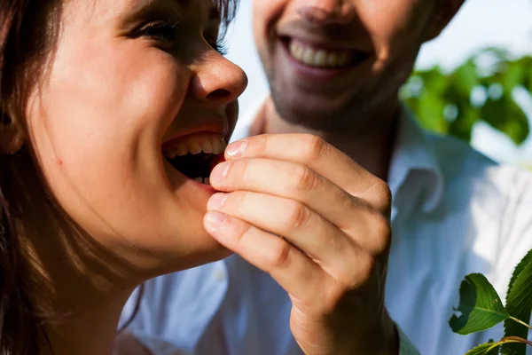 Happy couple eating cherries in summer — Stock Photo, Image