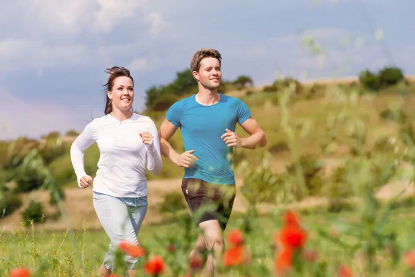 Joven pareja deportiva está corriendo fuera — Foto de Stock