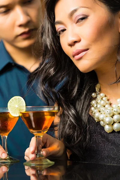 Asian man and woman at bar with cocktails — Stock Photo, Image