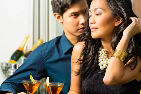 Asian man and woman at bar with cocktails — Stock Photo, Image