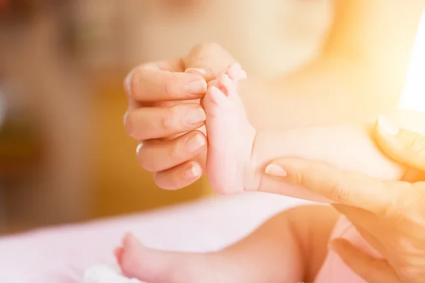 Bebé con madre, sosteniendo los pies — Foto de Stock