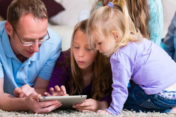 Семья играет с планшетным компьютером дома — стоковое фото
