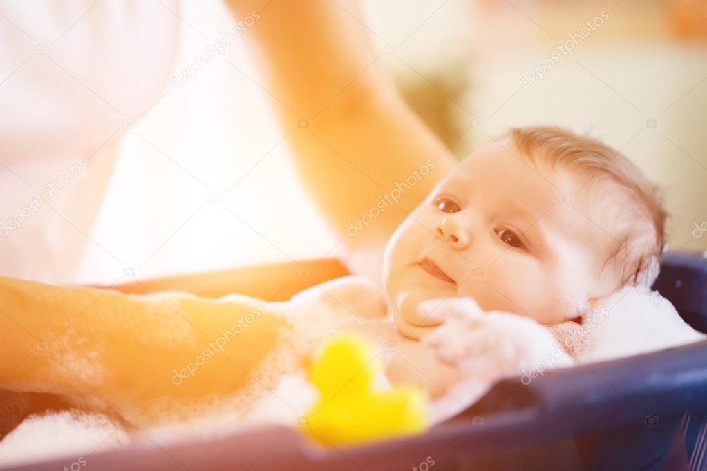 Mother is bathing her baby in bathtub