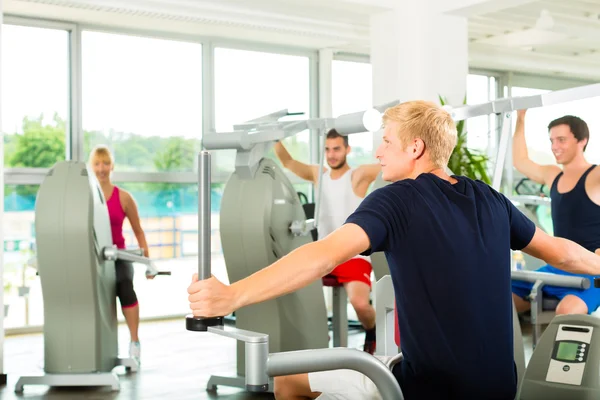 Gente en el gimnasio deportivo en la máquina de fitness — Foto de Stock