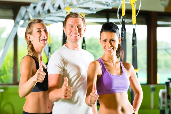 Gente en el gimnasio deportivo en el entrenador de suspensión — Foto de Stock