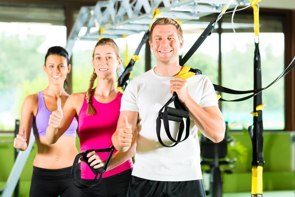 Gente en el gimnasio deportivo en el entrenador de suspensión — Foto de Stock