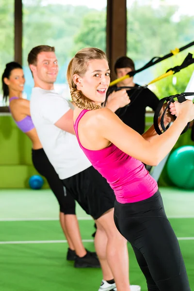 Gente en el gimnasio deportivo en el entrenador de suspensión — Foto de Stock