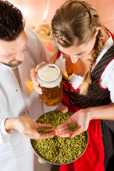 Cervecera y mujer con vaso de cerveza en cervecería — Foto de Stock