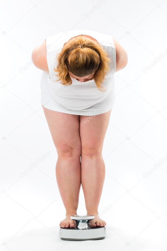 Obese young woman standing on a scale