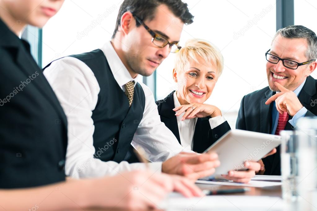 team working with tablet at meeting in office