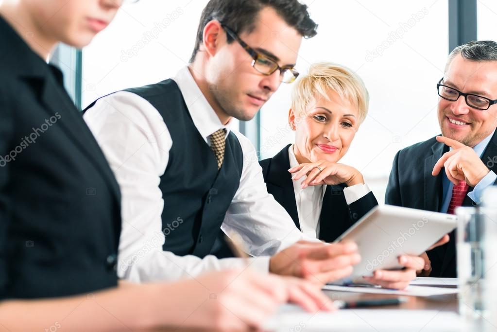 team working with tablet at meeting in office