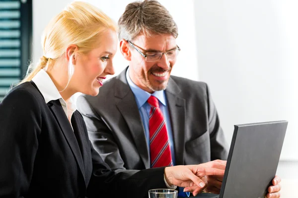 Geschäftsleute schauen in Absprache auf Laptop — Stockfoto