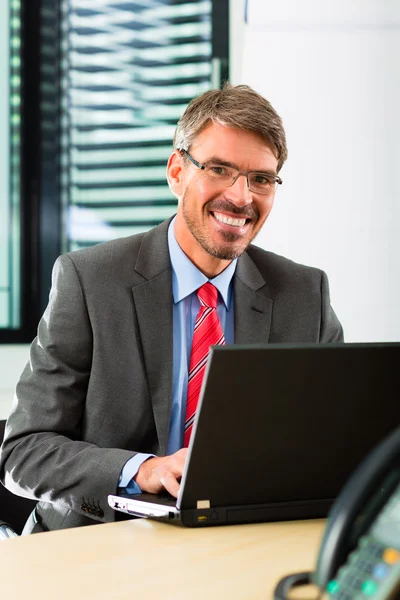 Empresario con portátil en su oficina de negocios —  Fotos de Stock