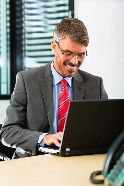 Zakenman met laptop in zijn kantoor — Stockfoto