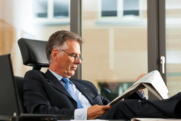 Boss in his office reading newspaper — Stock Photo, Image