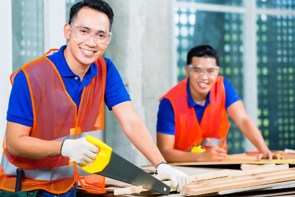 Builder sawing a wood board of building — Stock Photo, Image