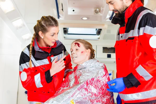 Ambulância ajudando mulher ferida — Fotografia de Stock