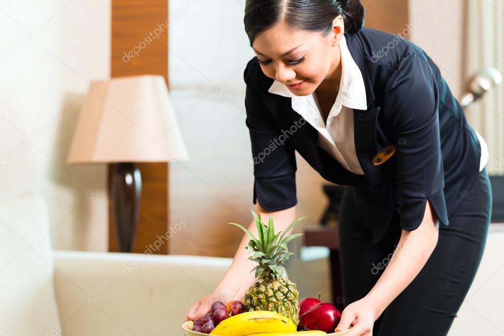 Chinese hotel housekeeper placing fruit