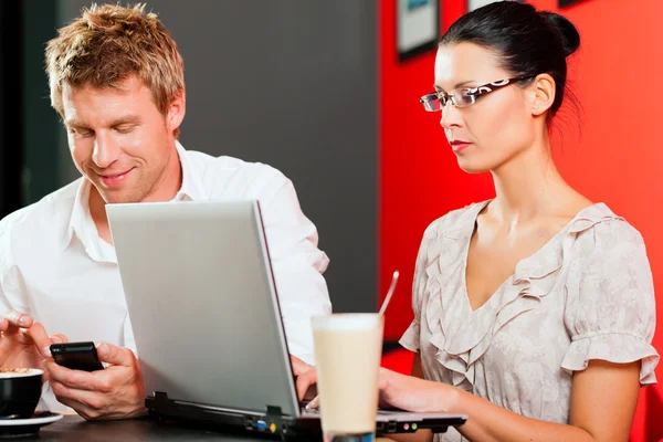 Couple en coffeeshop avec ordinateur portable et mobile — Photo