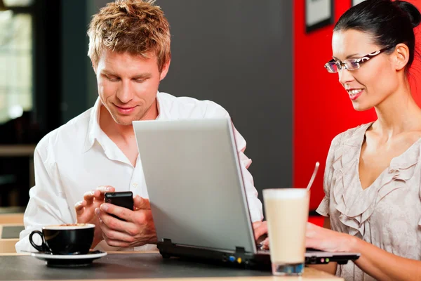 Pareja en coffeeshop con portátil y móvil — Foto de Stock