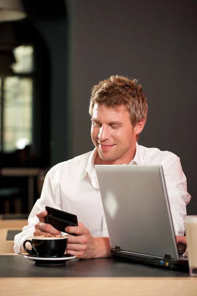 Paar im Coffeeshop mit Laptop und Handy — Stockfoto