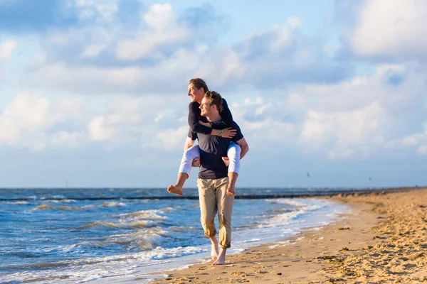 男人带女人背驮式在海滩 — 图库照片