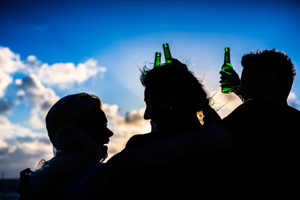 Друзья пьют пиво в бутылках на пляже — стоковое фото