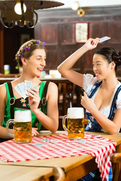 Friends drinking beer in Bavarian pub playing cards — Stock Photo, Image