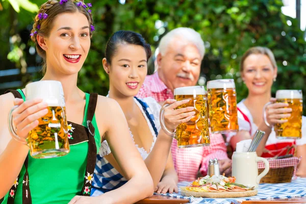 En el jardín de la cerveza - los amigos bebiendo la cerveza en la bavaria —  Fotos de Stock