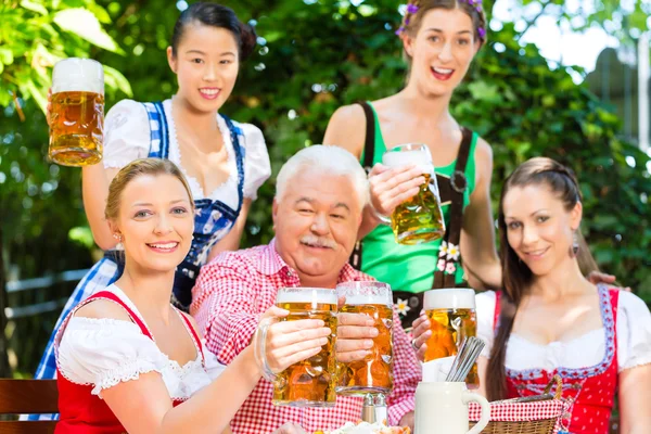 En el jardín de la cerveza - los amigos bebiendo la cerveza en la bavaria —  Fotos de Stock
