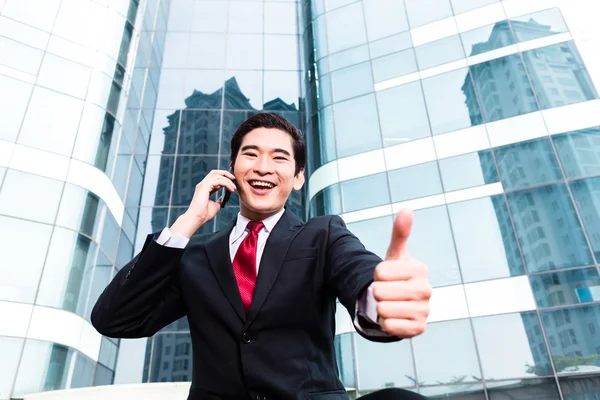 Asiatiska affärsman talar utanför till mobiltelefon — Stockfoto