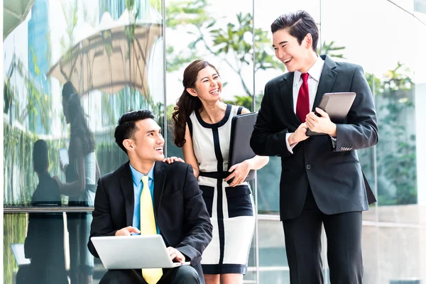 Asian businesspeople working outside on laptop — Stock Photo, Image